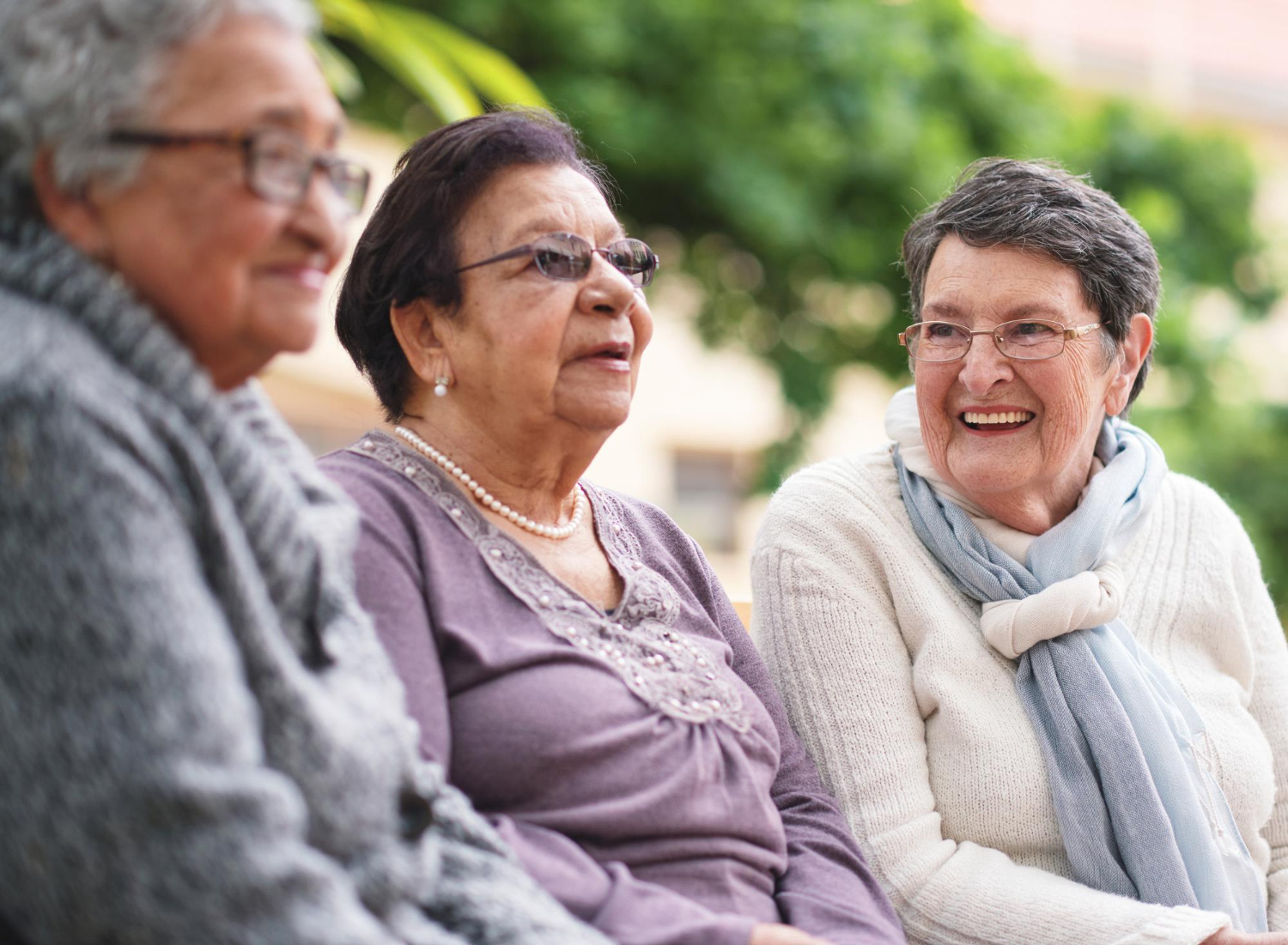 Mulheres idosas felizes sentadas no banco do parque sorrindo e aproveitando a aposentadoria juntas