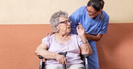 Idosa em momento de interação social com cuidadora em ambiente acolhedor de casa de repouso especializada em Alzheimer