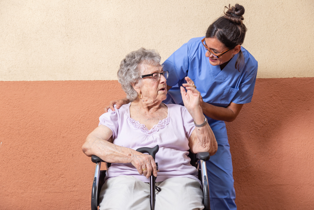 Idosa em momento de interação social com cuidadora em ambiente acolhedor de casa de repouso especializada em Alzheimer