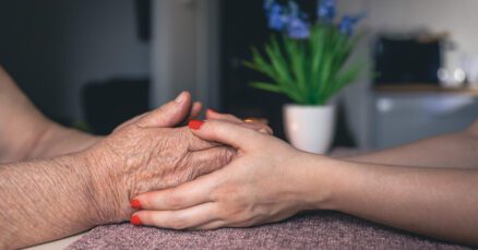 Cuidadora atenciosa segurando as mãos de uma senhora idosa com carinho, representando o suporte especializado e os cuidados para idosas com Alzheimer em SP na Casa de Repouso Viva Bem.