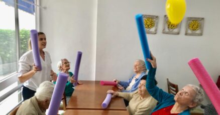 Blog 1 Idosas sorrindo durante atividade em grupo em casa de repouso, ilustrando a socialização na idade avançada