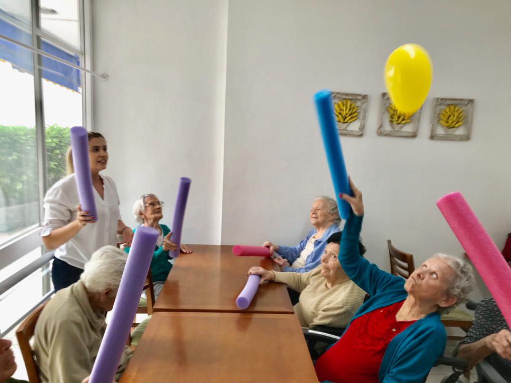 Home 2026 25 Idosas sorrindo durante atividade em grupo em casa de repouso, ilustrando a socialização na idade avançada